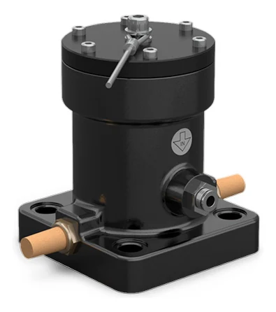 Stempelvibrator i den st&oslash;rste udf&oslash;relse, set skr&aring;t forfra: en mat sort cylinder p&aring; en n&aelig;sten kvadratisk fod med fors&aelig;nkede huller i hj&oslash;rnerne, en messingfarvet lydd&aelig;mper i hver side, en lufttilslutning med lynkobling p&aring; kroppen, og &oslash;verst et sort d&aelig;ksel med en krans af blanke skruer, en sekskantet m&oslash;trik i midten og en tynd stang skr&aring;t hen over d&aelig;kslet.